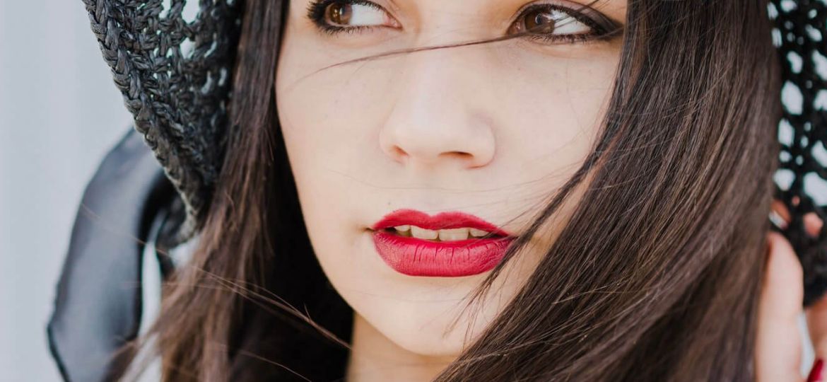 Close-up portrait of a young woman wearing a wide-brimmed hat, dreaming.