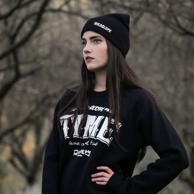 Young woman wearing black WildSlope beanie and sweatshirt, dreaming