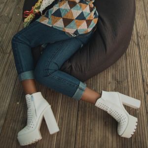 Woman in jeans and white platform boots relaxing on a beanbag chair.