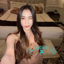 Attractive young woman winking, wearing a beige dress. KL Escort My.