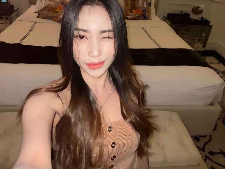 Attractive young woman winking, wearing a beige dress. KL Escort My.
