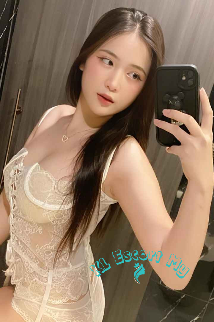 Attractive young woman in a lacy white bodysuit taking a selfie. KL Escort My