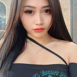 Attractive young woman with long dark hair, wearing a black off-the-shoulder top. KL Escort My
