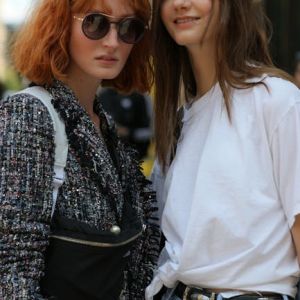 Two women posing together outdoors. One wears a tweed jacket; the other, a white t-shirt and jeans.